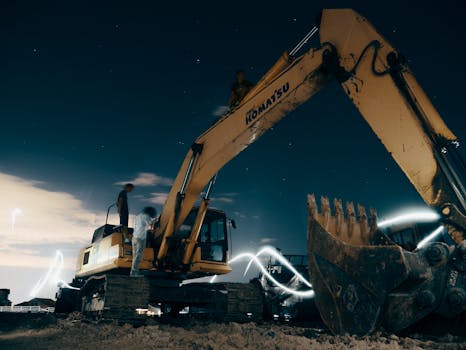 pexels-photo-2449603-2449603 A powerful excavator at a construction site under the night sky, with workers around.